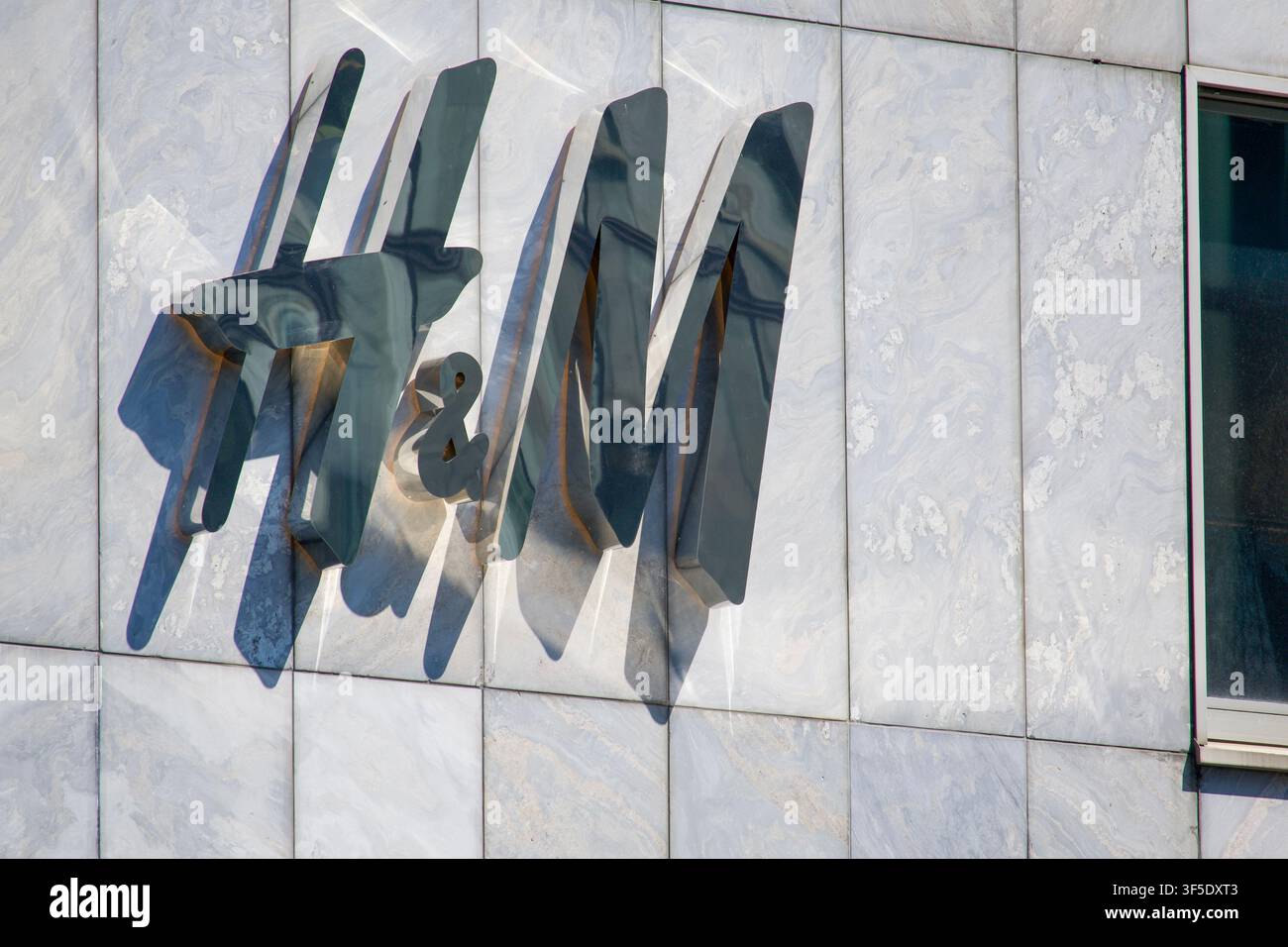 Zurigo, Svizzera - 30 luglio 2026: Vista ravvicinata del logo 3D metallico H&M montato su una facciata in pietra di marmo di un negozio di abbigliamento al dettaglio Foto Stock