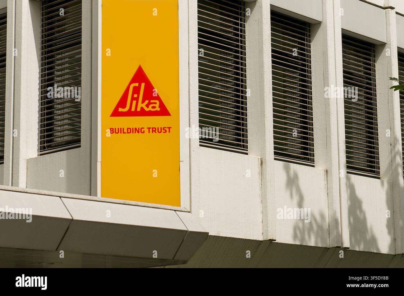 Baar, Zug, Svizzera - 16 giugno 2026: Vista del cartello con il logo aziendale Sika e dello slogan “Building Trust” su una colonna murale della sede centrale Foto Stock