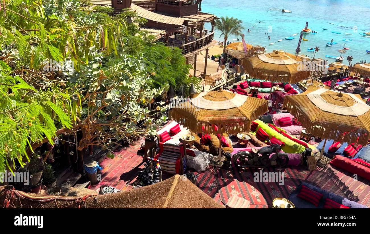 SHARM EL SHEIKH, EGITTO - 20 OTT. 2025: Vista ad alta angolazione di un caffè sulla scogliera con ombrelloni di paglia che si affacciano sul mare blu a Sharm el Sheikh, Egitto. Foto Stock