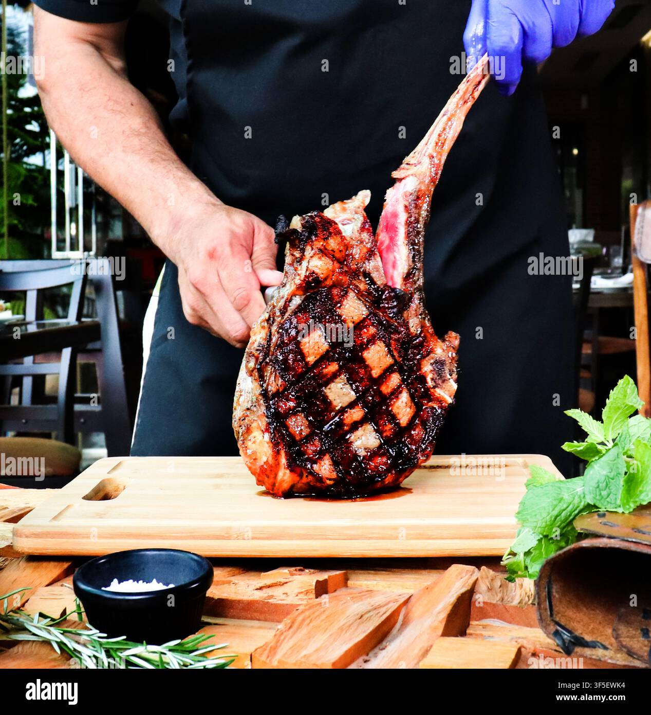 Deliziosa fetta di carne Tomahawk accompagnata da pomodorini ciliegia e asparagi e pepe su sfondo rustico Foto Stock