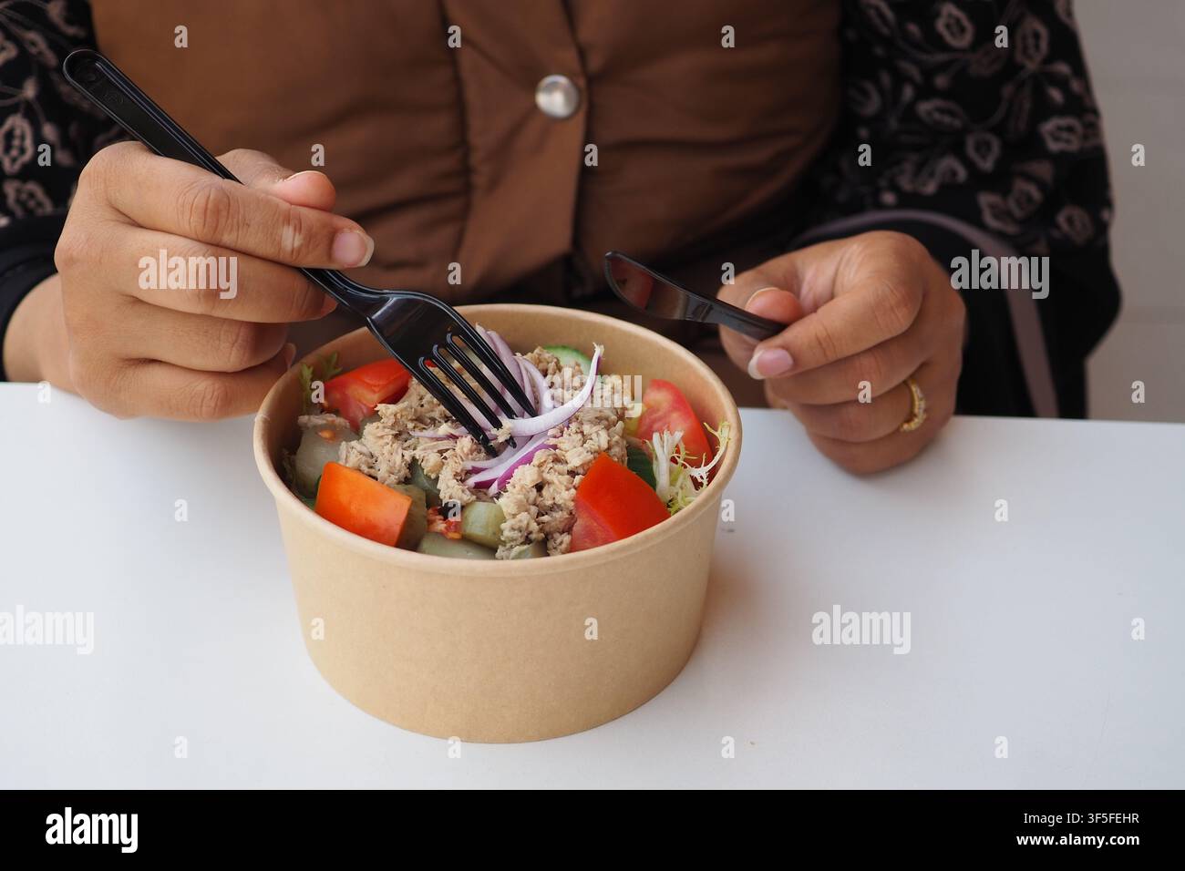 Mangiare una ciotola di insalata a un tavolo da pranzo Foto Stock