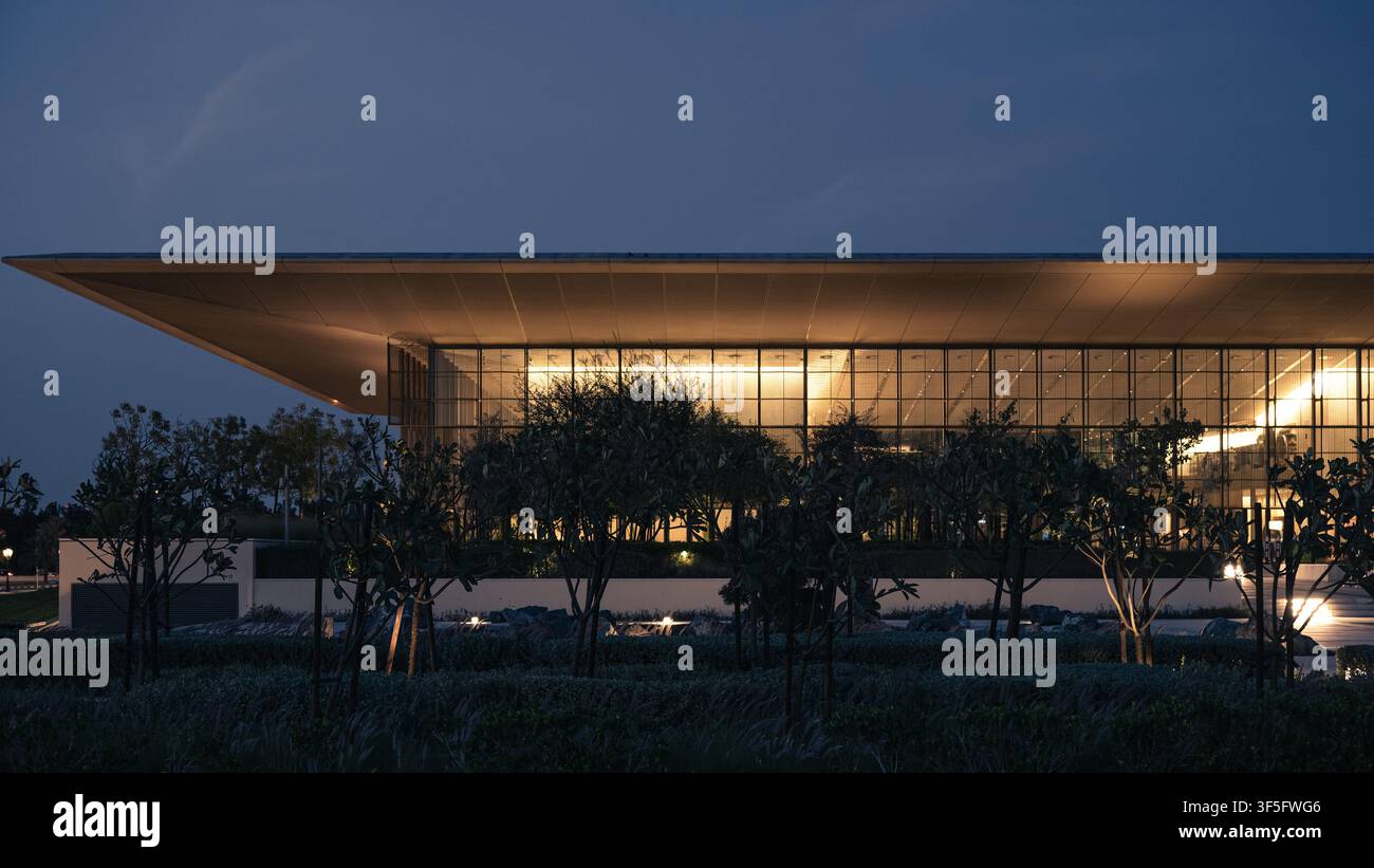 Casa della Saggezza a Sharjah, Emirati Arabi Uniti, progettata da Foster + Partners, illuminata nell'ora blu e circondata da giardini paesaggistici. Foto Stock