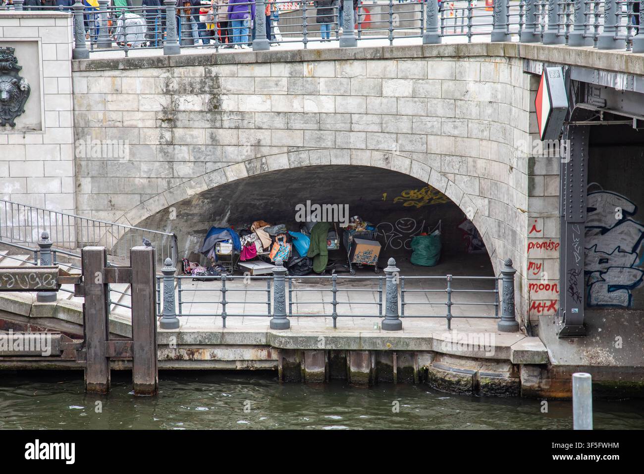 Effetti di senzatetto sotto un arco di ponte sulle rive del fiume Spree a Berlino, Germania Foto Stock