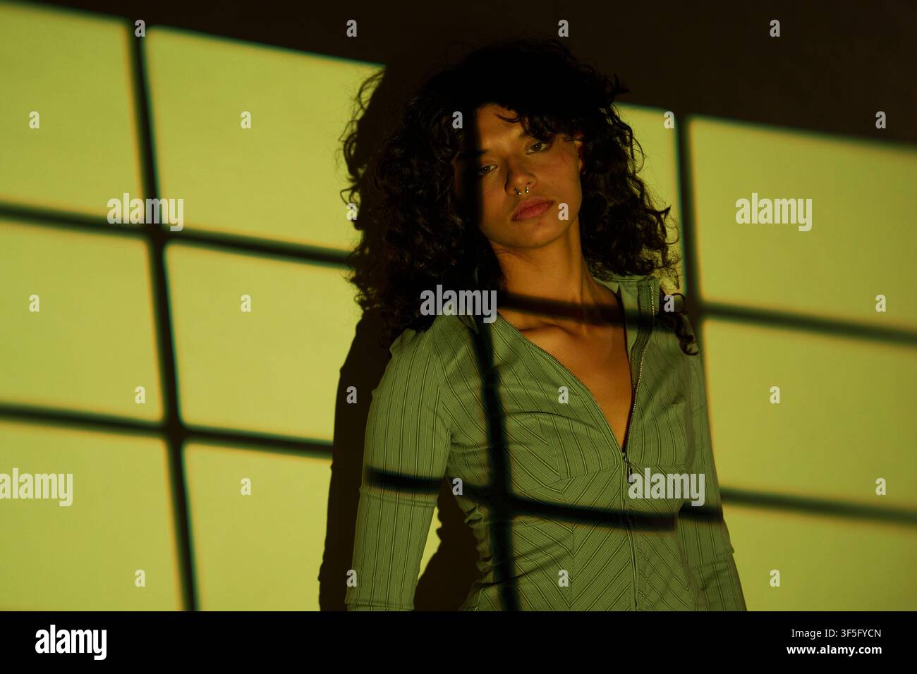 Donna in piedi con motivi di ombre proiettati sul suo corpo e sullo sfondo Foto Stock