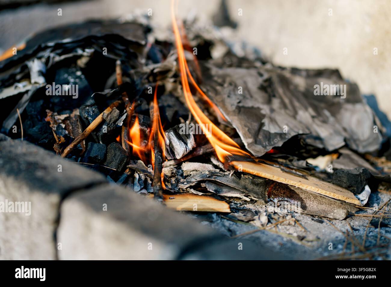 Legna da ardere e carbone che bruciano all'interno di una griglia da barbecue in mattoni all'aperto. Concetto di cucina, barbecue, calore, vita all'aperto e cucina tradizionale Foto Stock