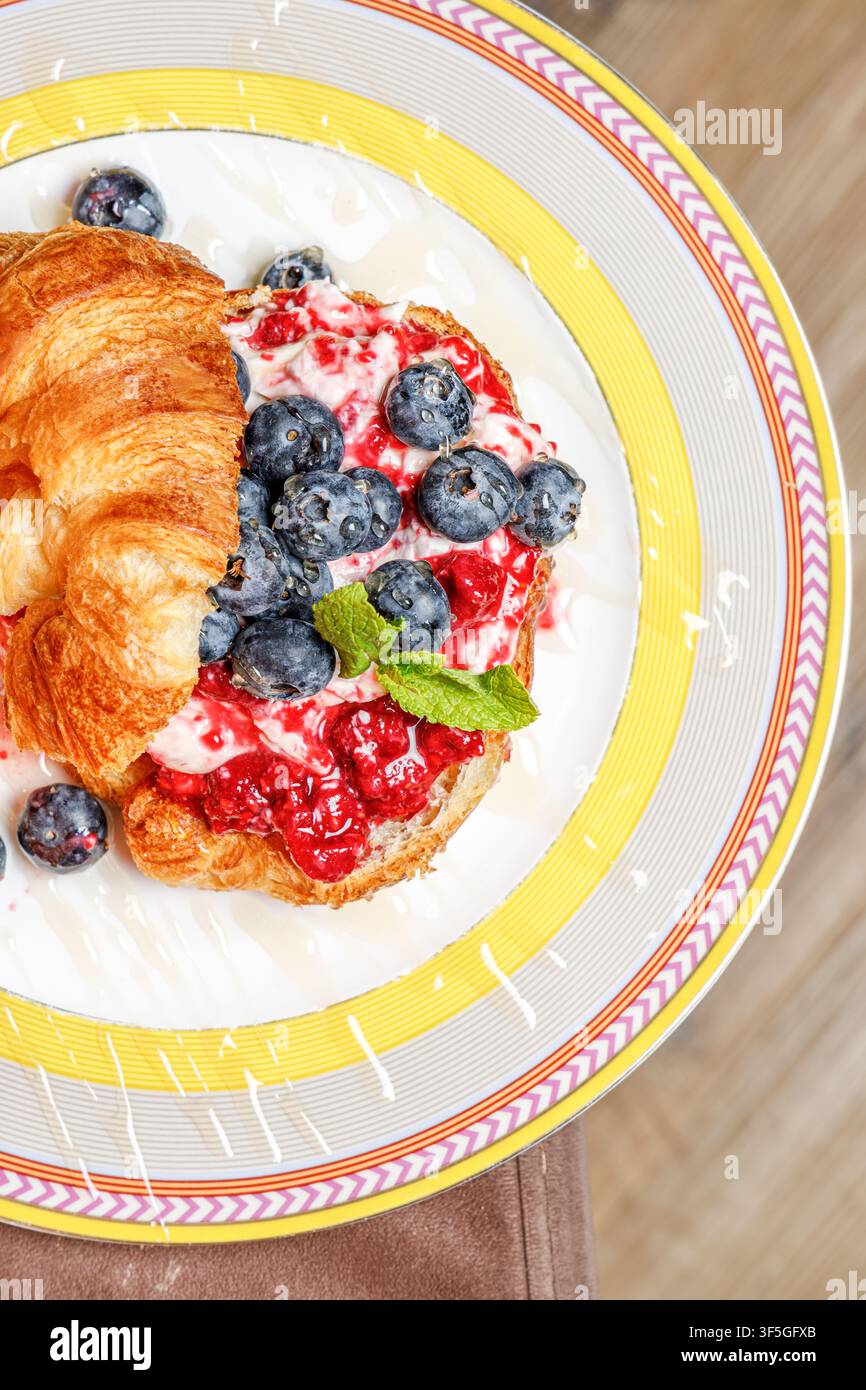 Croissant gourmet con formaggio burrata, bacche fresche e miele Foto Stock