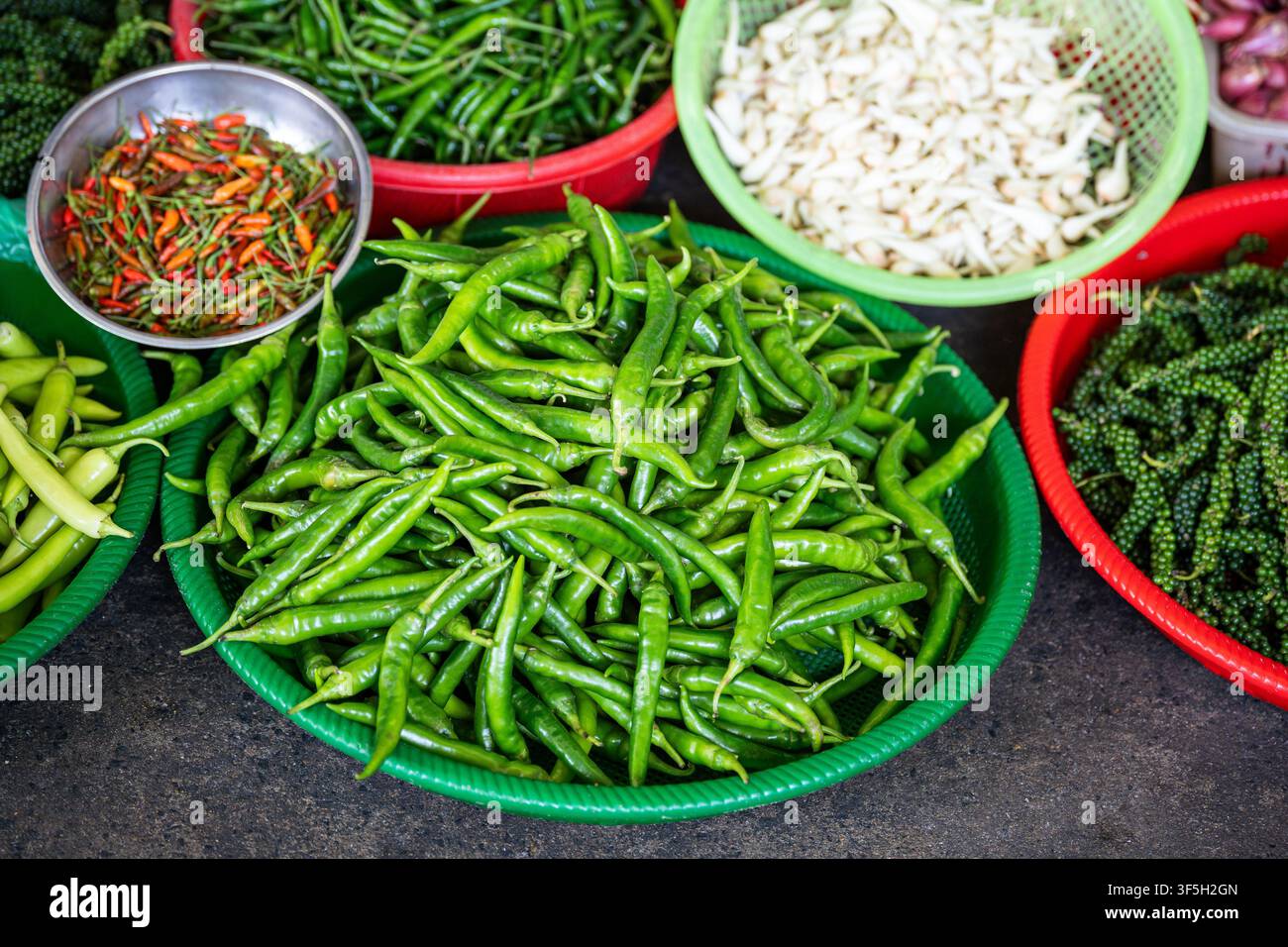 Ciotole piene di peperoncini freschi piccanti, aglio e grani di pepe verdi in vendita al mercato di strada. Foto Stock