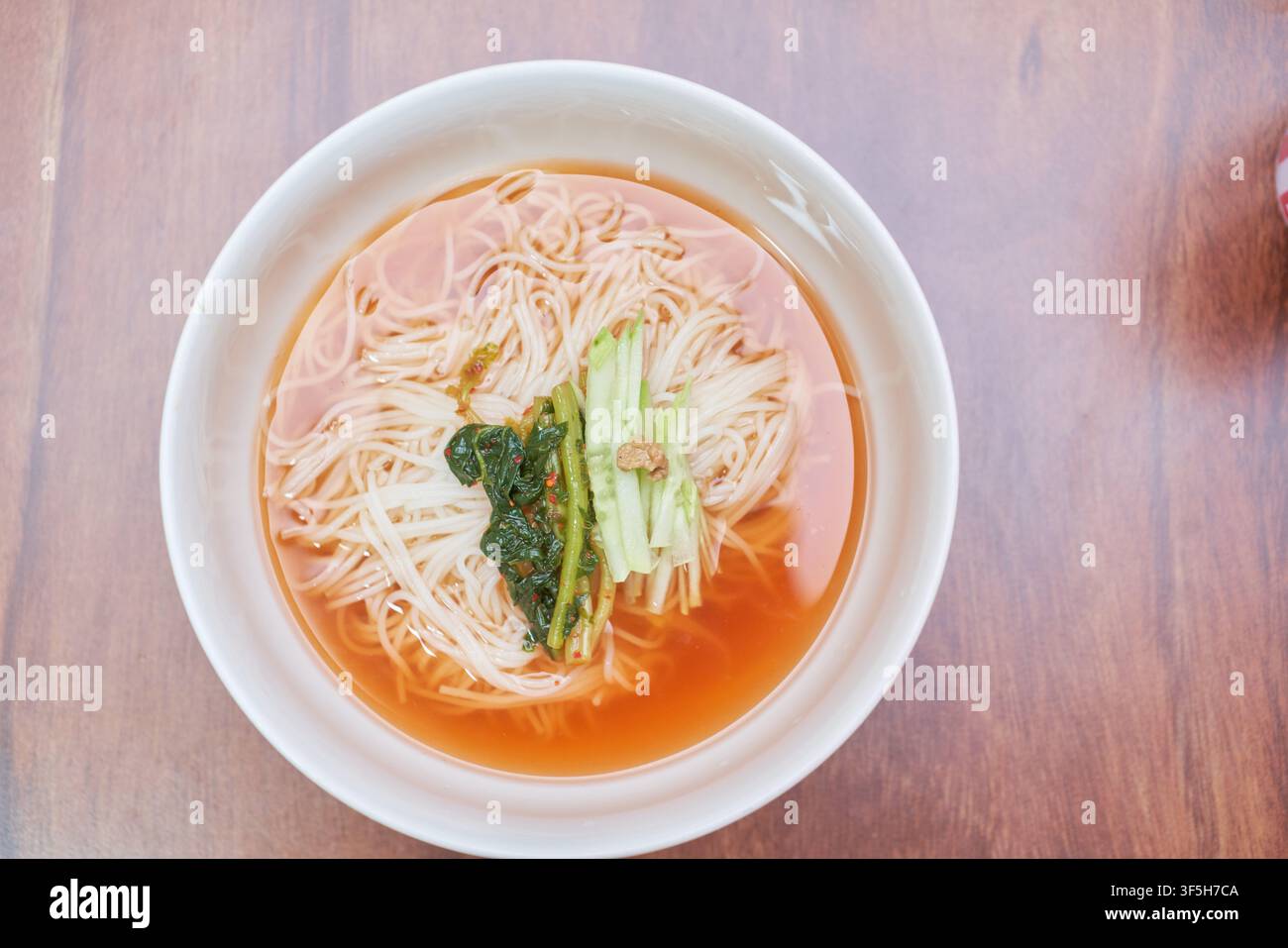 Yeolmu guksu, una zuppa di noodle coreana fredda con kimchi al ravanello verde, cetriolo e salsa di senape, servita come piatto rinfrescante estivo. Foto Stock