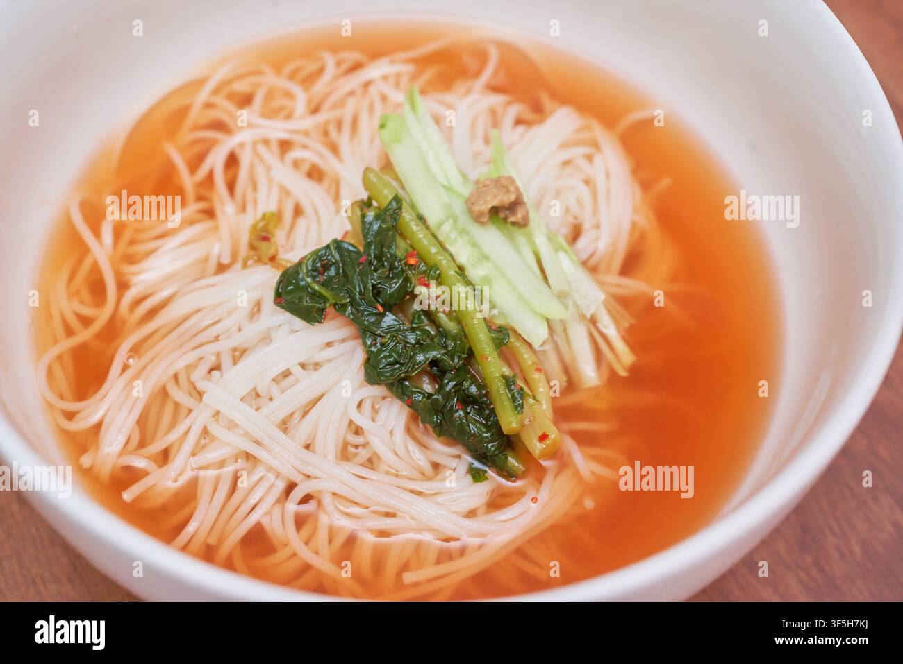 Yeolmu guksu, una zuppa di noodle coreana fredda con kimchi al ravanello verde, cetriolo e salsa di senape, servita come piatto rinfrescante estivo. Foto Stock