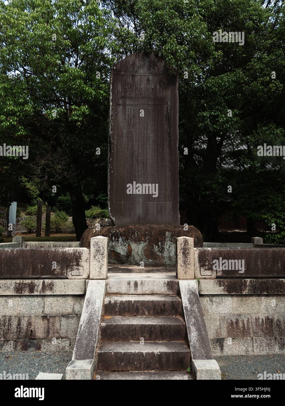 Stele commemorativa in pietra su piattaforma in pietra a gradini circondata da alberi a Higashiyama, Kyoto, Giappone Foto Stock