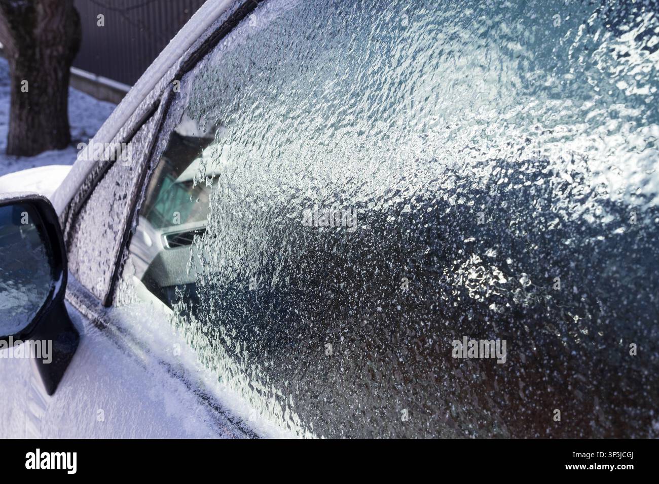 Finestra del veicolo ricoperta da uno spesso strato di ghiaccio dopo una fredda notte invernale, che illustra il gelo, la brina e la manutenzione stagionale del veicolo. Foto Stock
