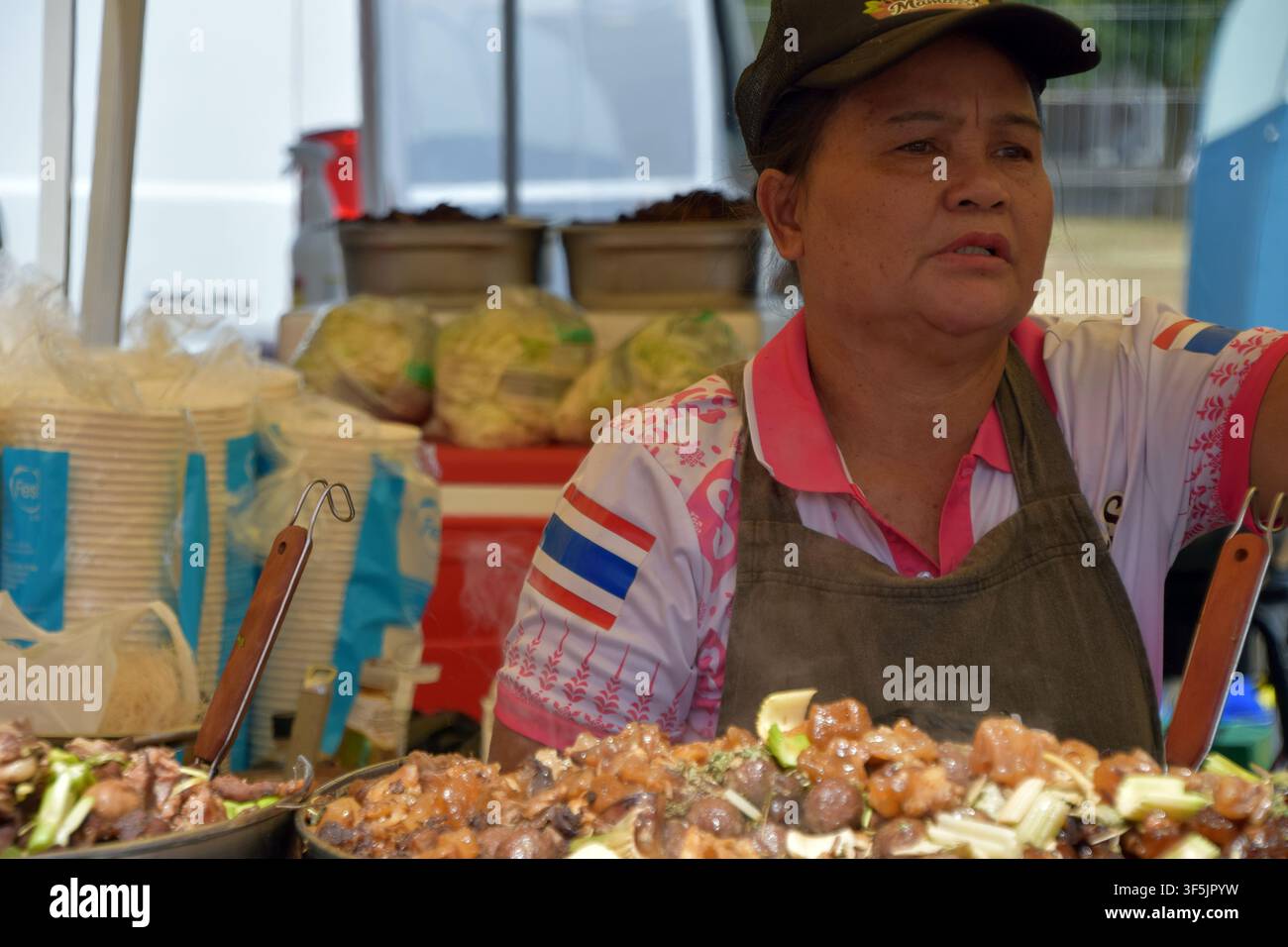 Venditore di street food thailandese serve piatti appena preparati a un festival gastronomico all'aperto Foto Stock