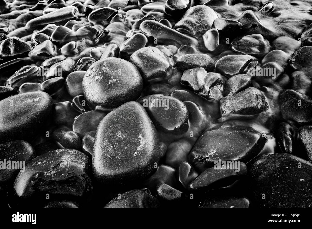 Le pietre levigate dal Short Sands Creek si trovano dove il torrente sfocia sulla spiaggia di Short Sands nell'Oswald West State Park vicino ad Arch Cape, Oregon. Foto Stock