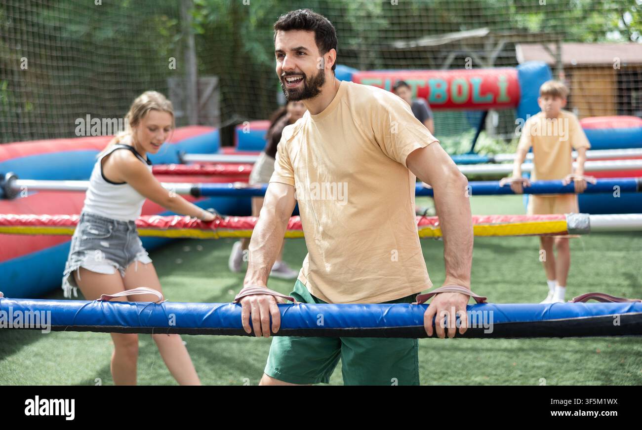 Amici giocano a calcio balilla, partita di calcio in diretta, in un parco divertimenti in una giornata estiva Foto Stock