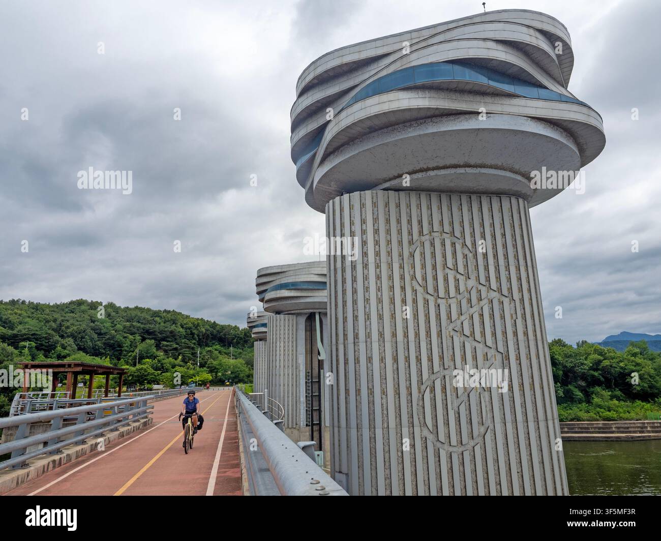 Ciclista che attraversa un muro di diga a Sangju lungo il percorso ciclabile del fiume Nakdong Foto Stock