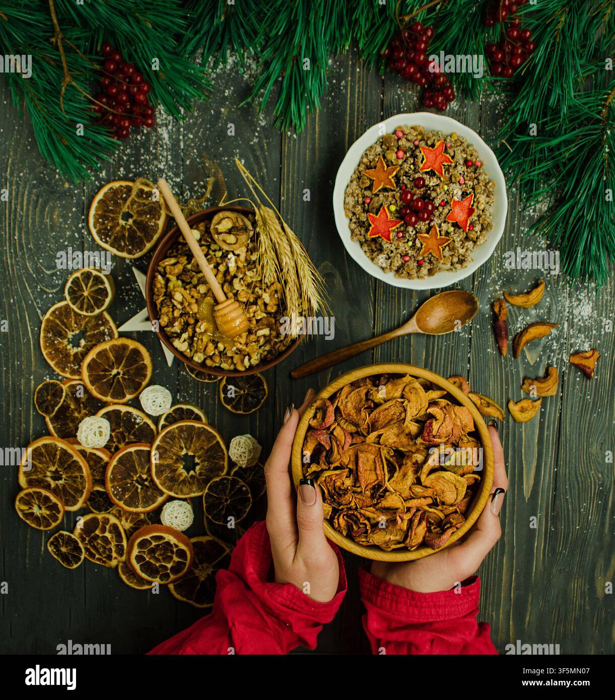 Mani in maniche festive colorate reggono una ciotola bianca ripiena di kutia, tradizionale porridge di grano natalizio ucraino, ricoperta di frutta secca e bacche Foto Stock