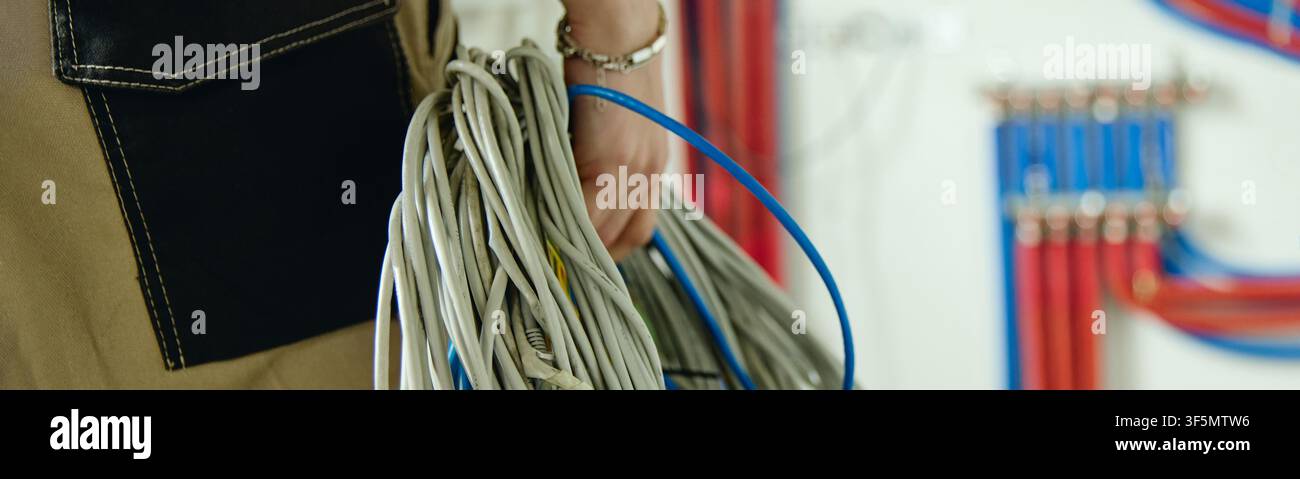 Elettricista che tiene dei cavi durante la ristrutturazione della casa Foto Stock