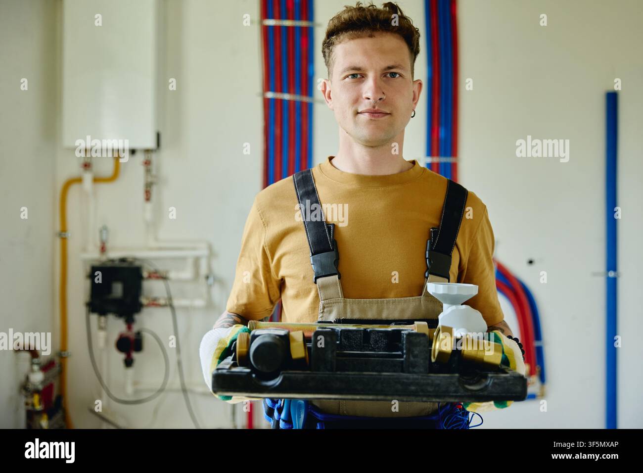 Ritratto di un uomo che tiene attrezzi idraulici durante la ristrutturazione della casa Foto Stock