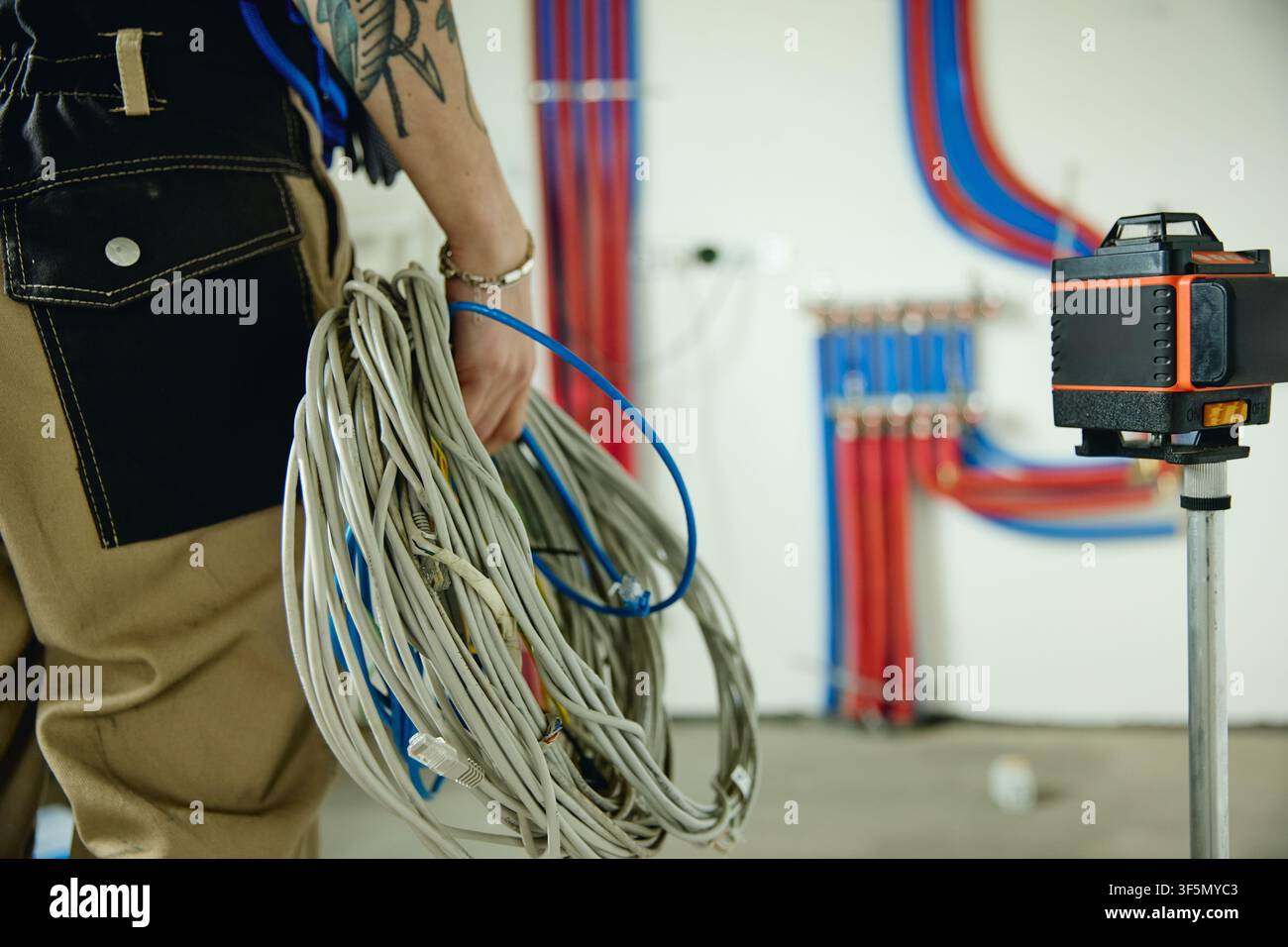 Elettricista che tiene i cavi durante la ristrutturazione della casa e l'installazione dell'impianto idraulico Foto Stock