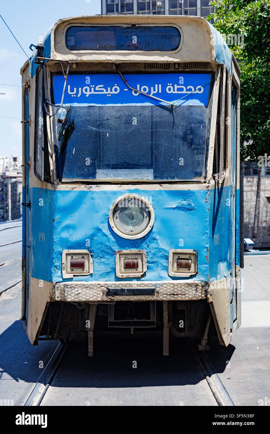 Un tram vintage blu e bianco si trova sui binari ad Alessandria, in Egitto, il suo cartello di direzione frontale è scritto in caratteri arabi e recita Stazione di Raml verso Foto Stock