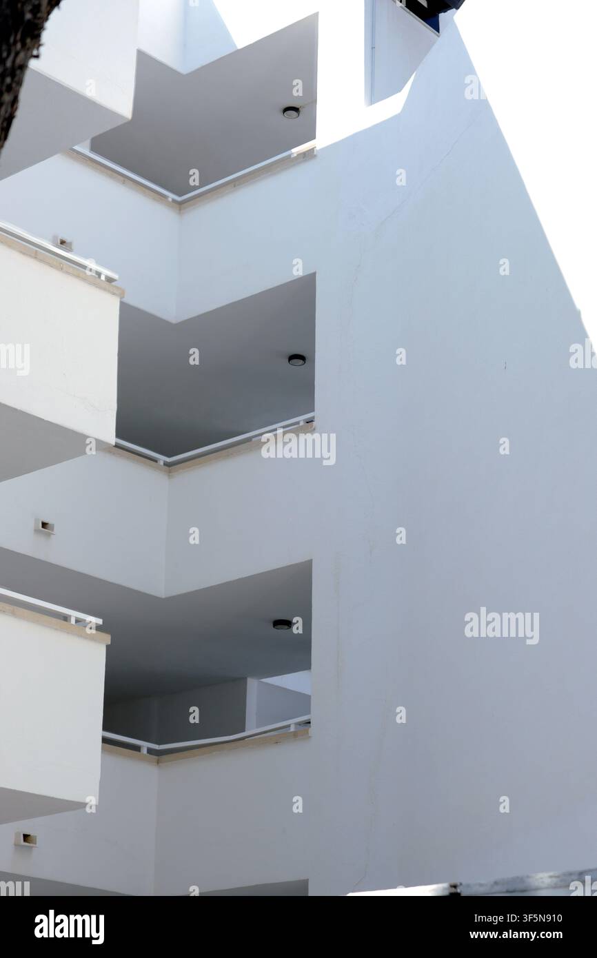 L'architettura del balcone dell'hotel forma una composizione geometrica minimalista di terrazze bianche impilate e ombre profonde su un edificio moderno di resort. Magaluf, M Foto Stock