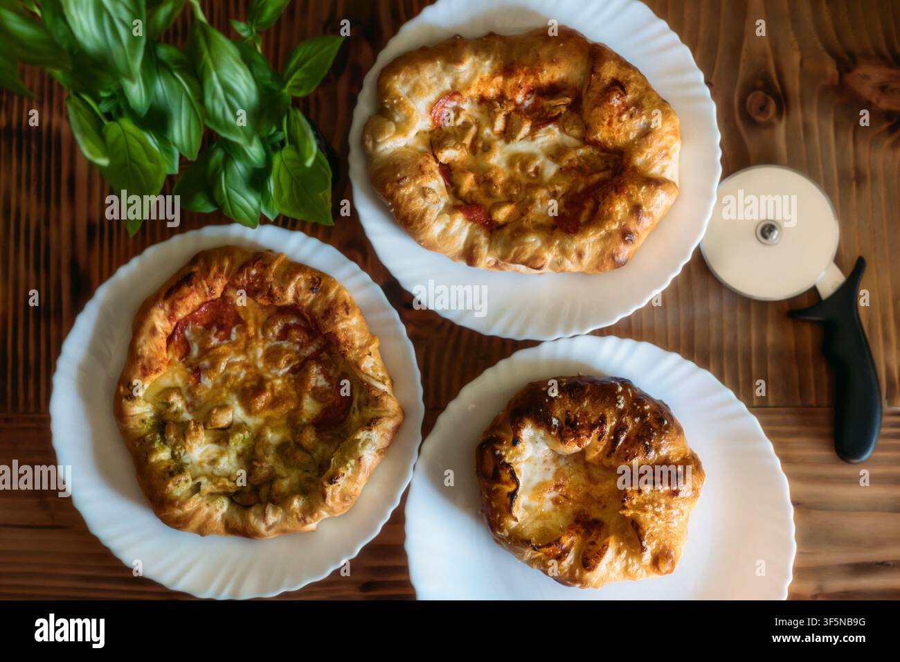 Tre pizze personali rustiche su un tavolo di legno Foto Stock
