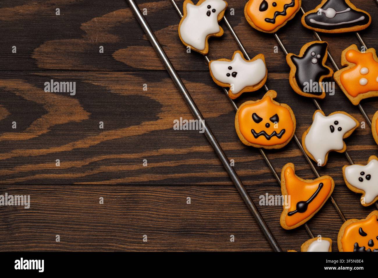 Assortimento di biscotti di zenzero fatti in casa per Halloween decorati con glassa arancione, bianca e nera, a forma di zucche, fantasmi, pipistrelli e cappelli da strega Foto Stock