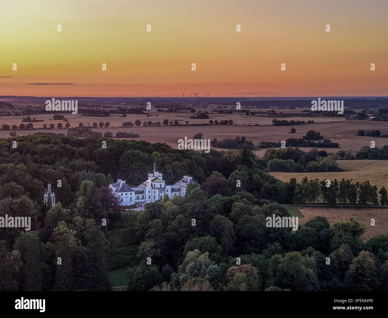 Vista aerea di un maniero storico di campagna circondato dalla foresta al tramonto colorato Foto Stock