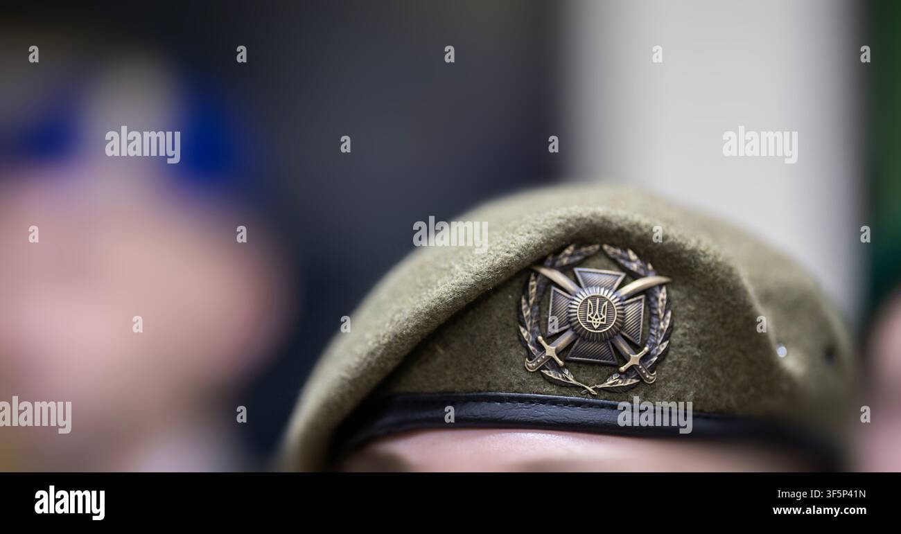 Kiev, Ucraina - 19 giugno 2026: Primo piano di un berretto olivastro delle forze di terra ucraine con un emblema a croce di metallo e spade durante una cerimonia di premiazione militare Foto Stock