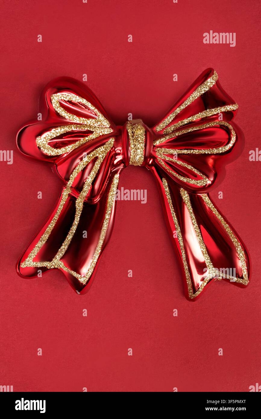 Palla di Natale in vetro rossa a forma di arco su sfondo rosso da studio Foto Stock