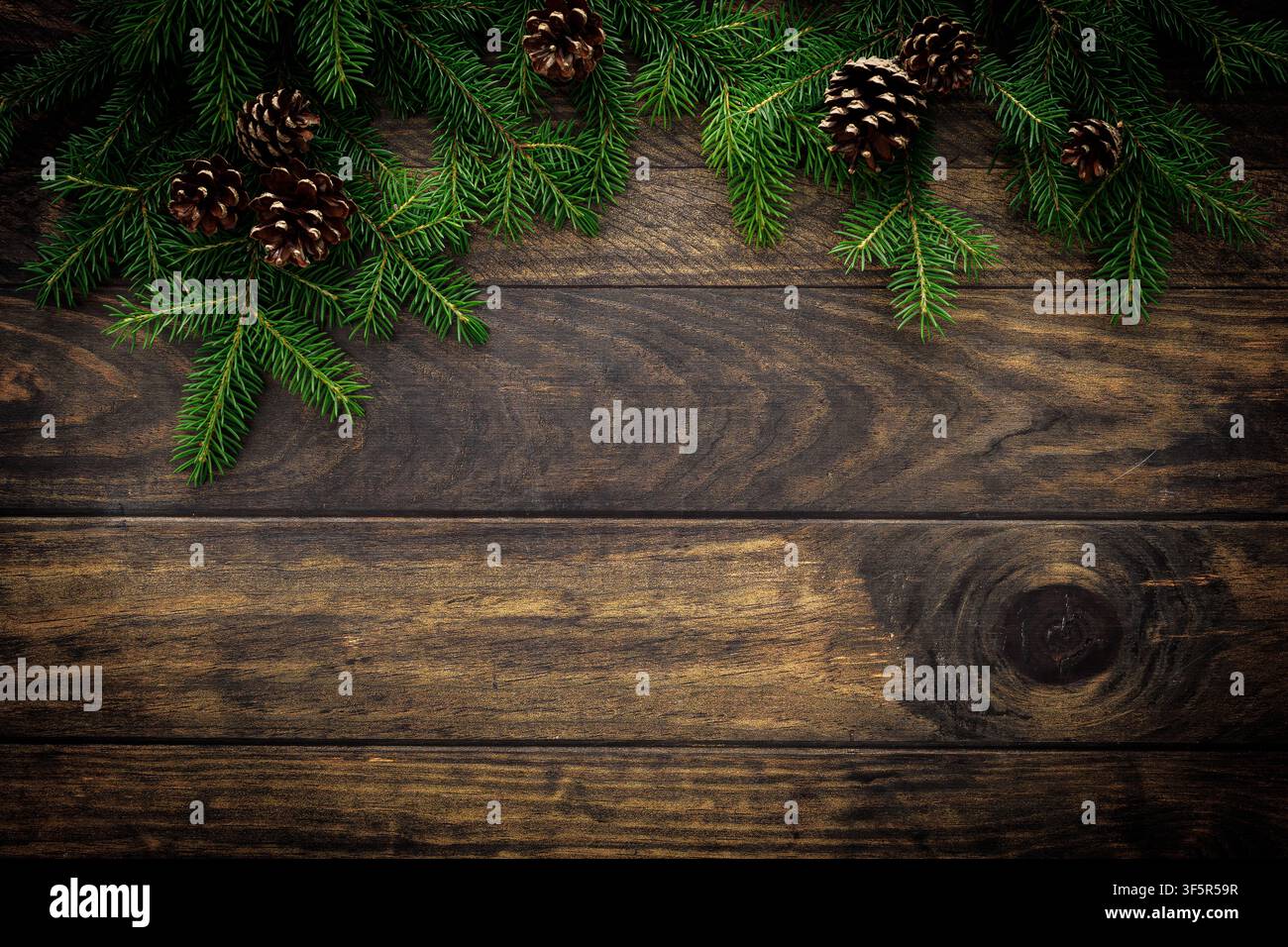 Sfondo natalizio con rami di abete e pigne su tavole di legno rustico, decorazione natalizia Foto Stock