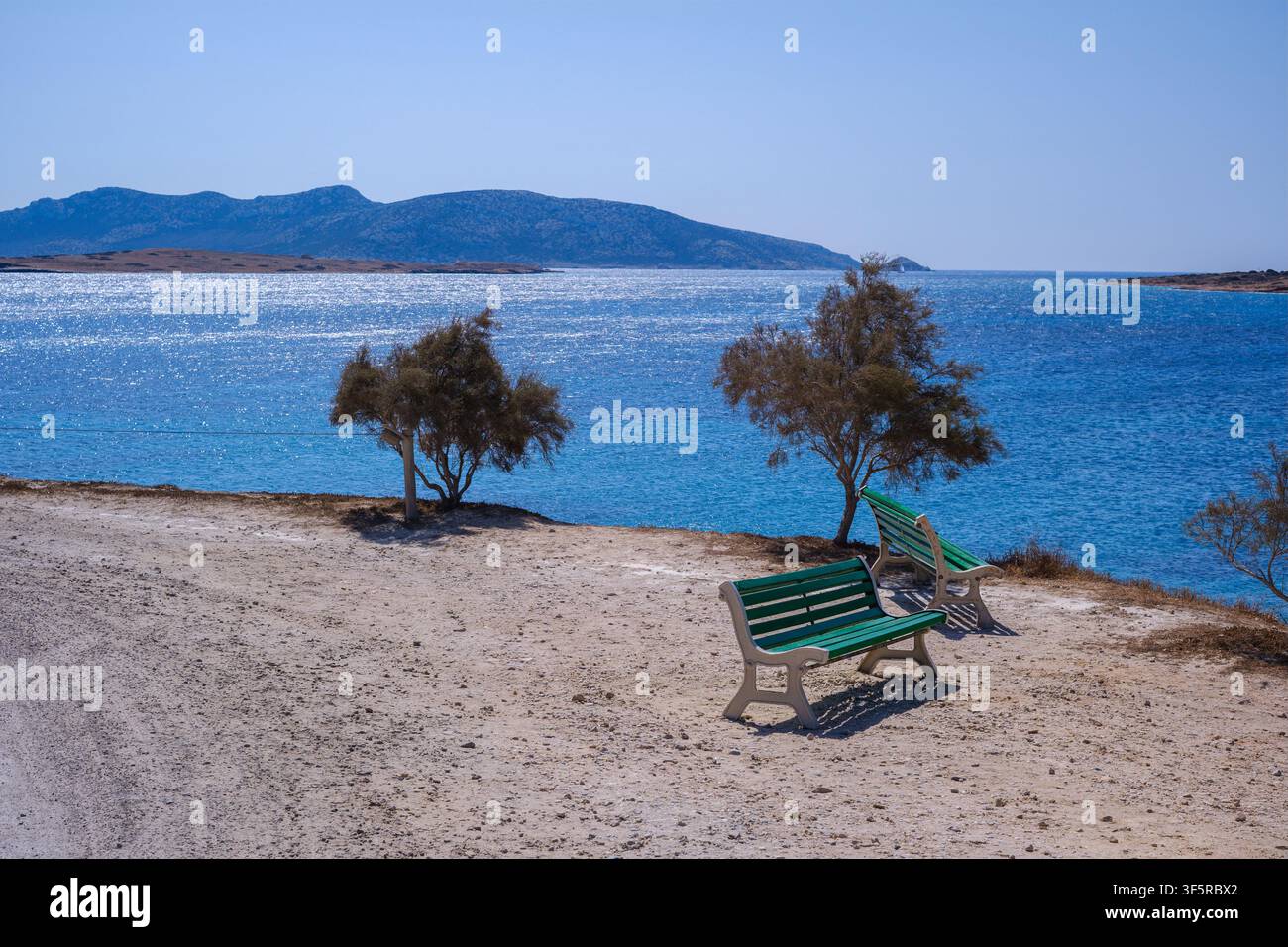 Panchine verdi posizionate su una spiaggia di sabbia di fronte al mare a Koufonisia, Grecia Foto Stock