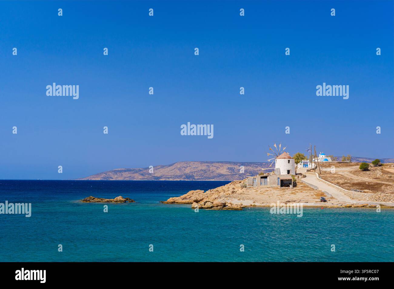 Mulino su una costa rocciosa con acqua turchese a Koufonisia, Koufonisia, Grecia Foto Stock