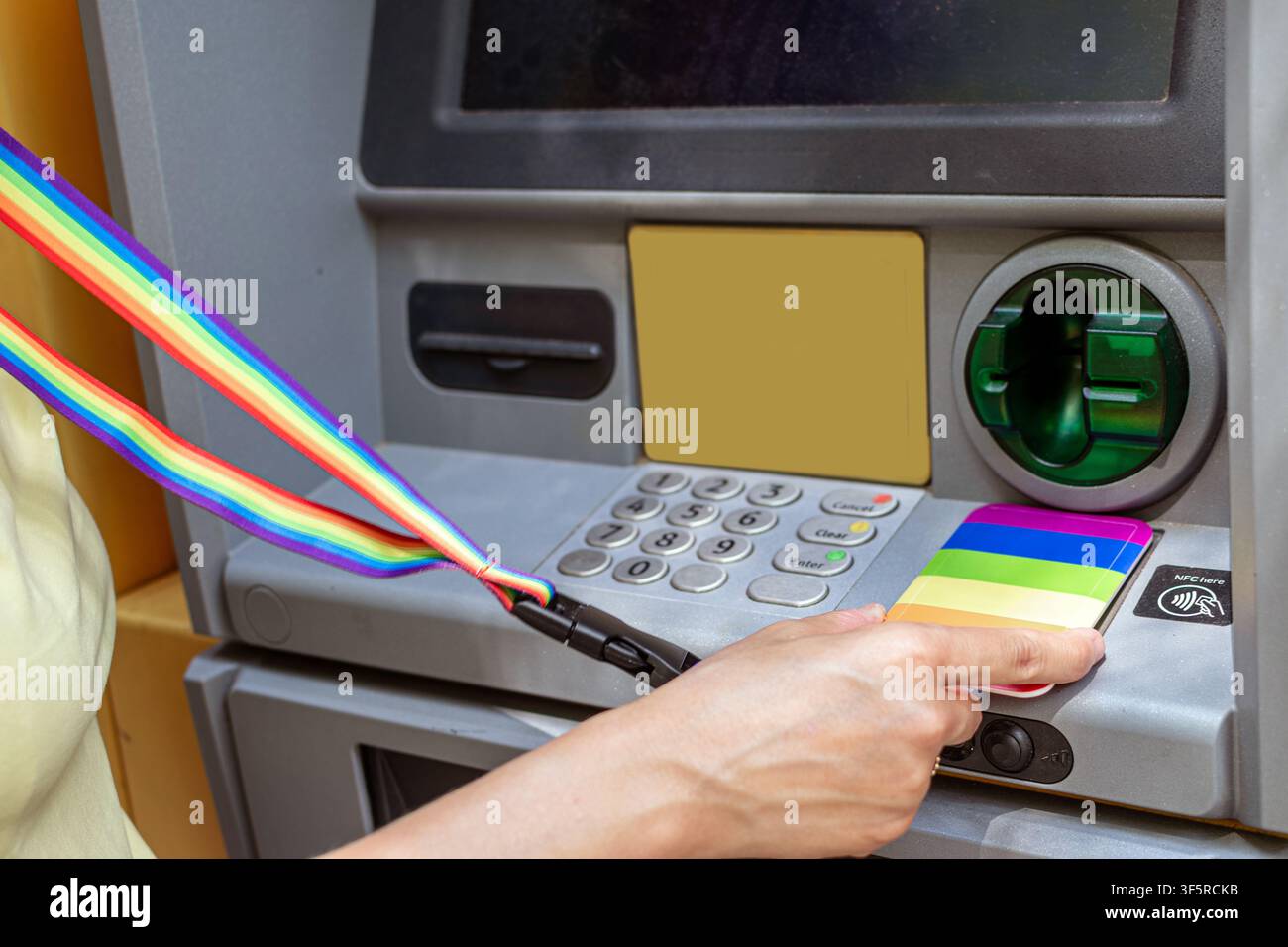 Persona che utilizza una carta di credito arcobaleno per un pagamento contactless al bancomat Foto Stock