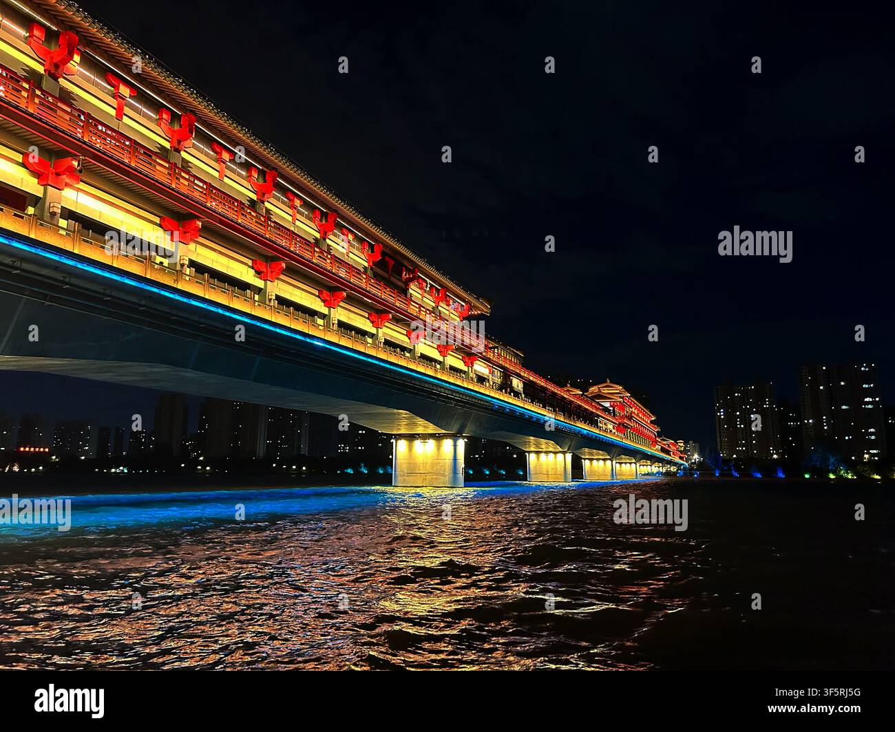 Vista del ponte antico del traghetto di Xianyang illuminato di notte, con lanterne rosse tradizionali e una vivace illuminazione blu sul fiume a Xianyan Foto Stock