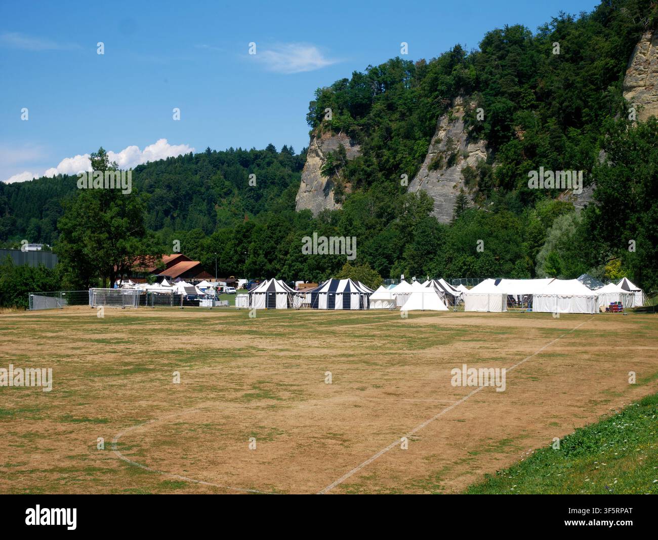 Camping in una valle verde circondata da scogliere rocciose e colline boschive Foto Stock