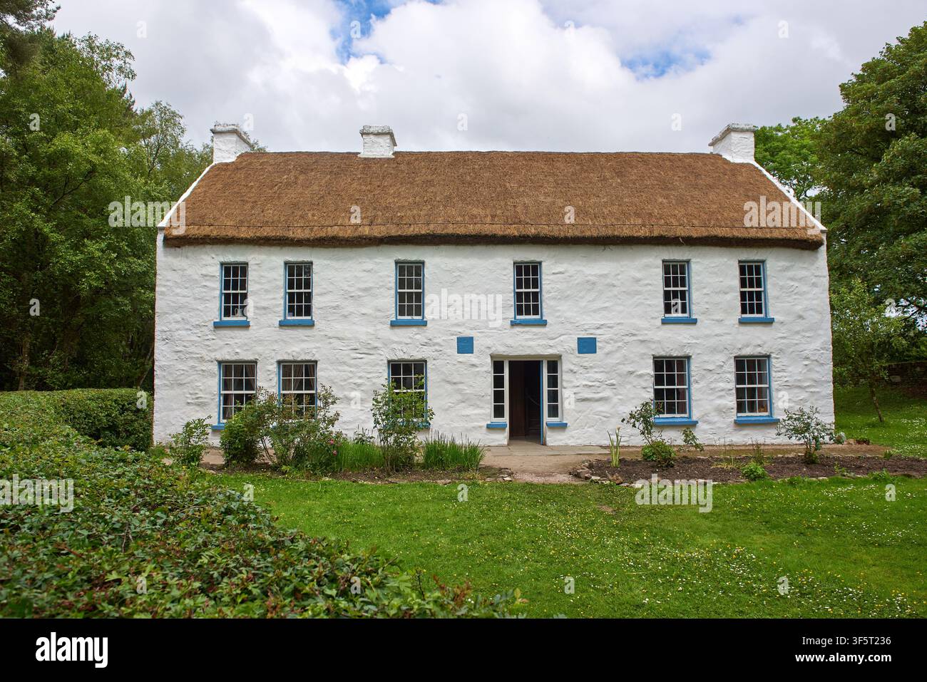 Casa tradizionale a due piani con tetto di paglia e finestre a ghigliottina con cornici blu all'Ulster American Folk Park vicino a Omagh, Contea di Tyrone, Irlanda del Nord Foto Stock