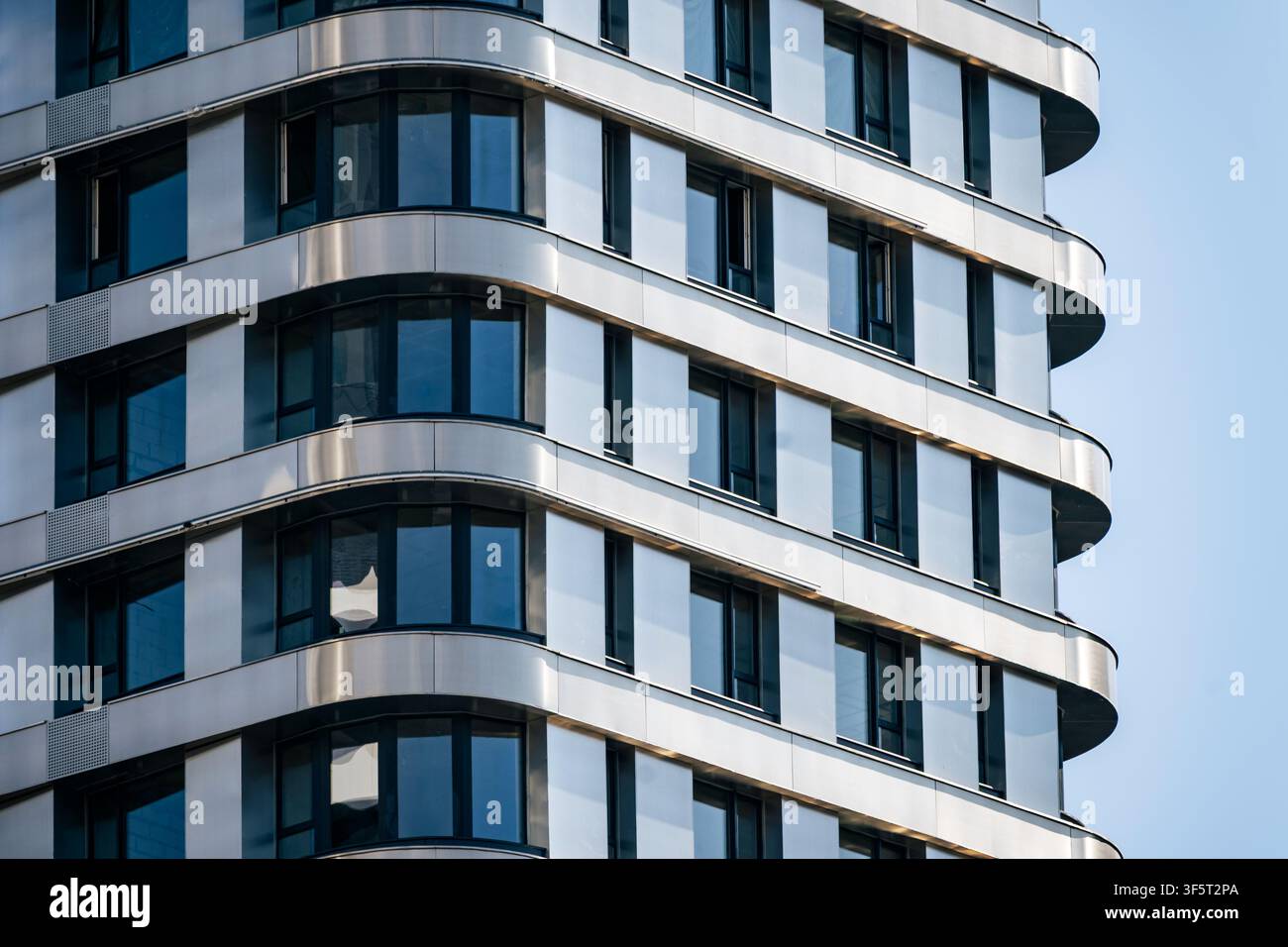 Edificio residenziale moderno con angolo in vetro arrotondato, elegante facciata in metallo e architettura contemporanea. Immobiliare urbana premium esterno con chiaro Foto Stock