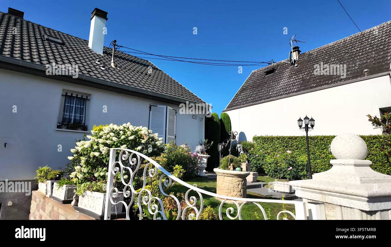 STRASBOURG, FRANCIA - 15 LUGLIO 2026: Un cortile anteriore con un cancello decorativo in ferro battuto, un pozzo in pietra e un giardino fiorito a Strasburgo. Foto Stock