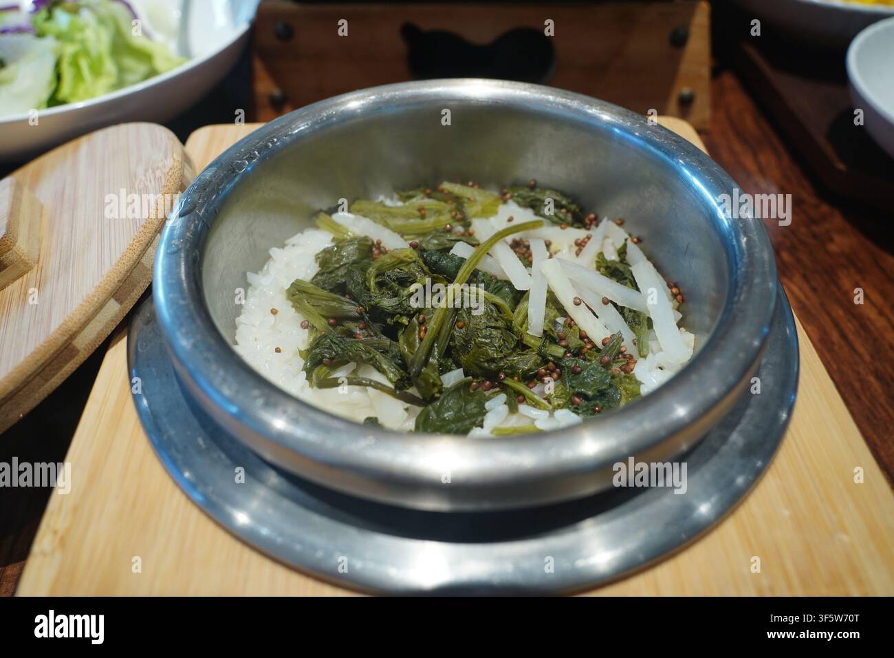 Riso al cardo coreano, Gondre-bap, tradizionale riso sano cotto in pentola di pietra con erbe condite Foto Stock