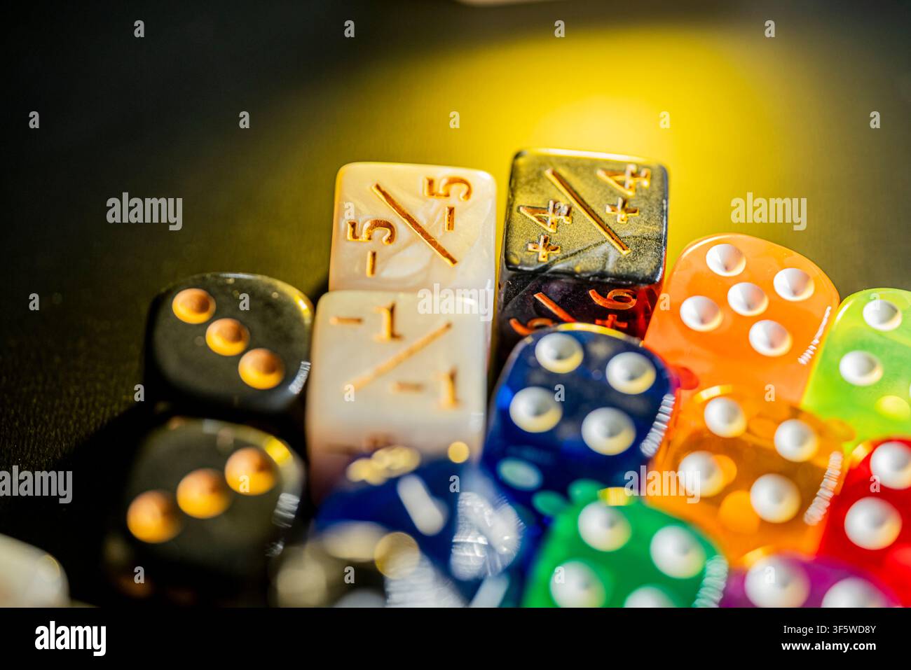 Pile di dadi traslucidi e vivaci a sei facce e gettoni di gioco specifici su una superficie scura Foto Stock