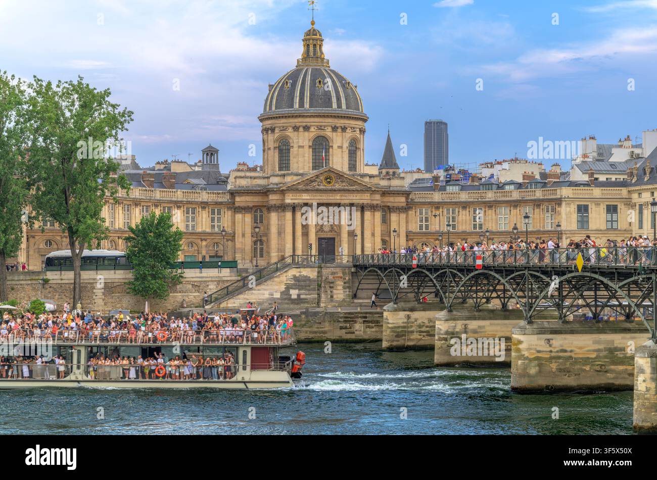 Barche turistiche che navigano sotto il Pont des Arts (o Passerelle des Arts), un ponte pedonale sulla Senna a Parigi. L’Istituto di Francia con la sua cupola è al centro. Foto Stock