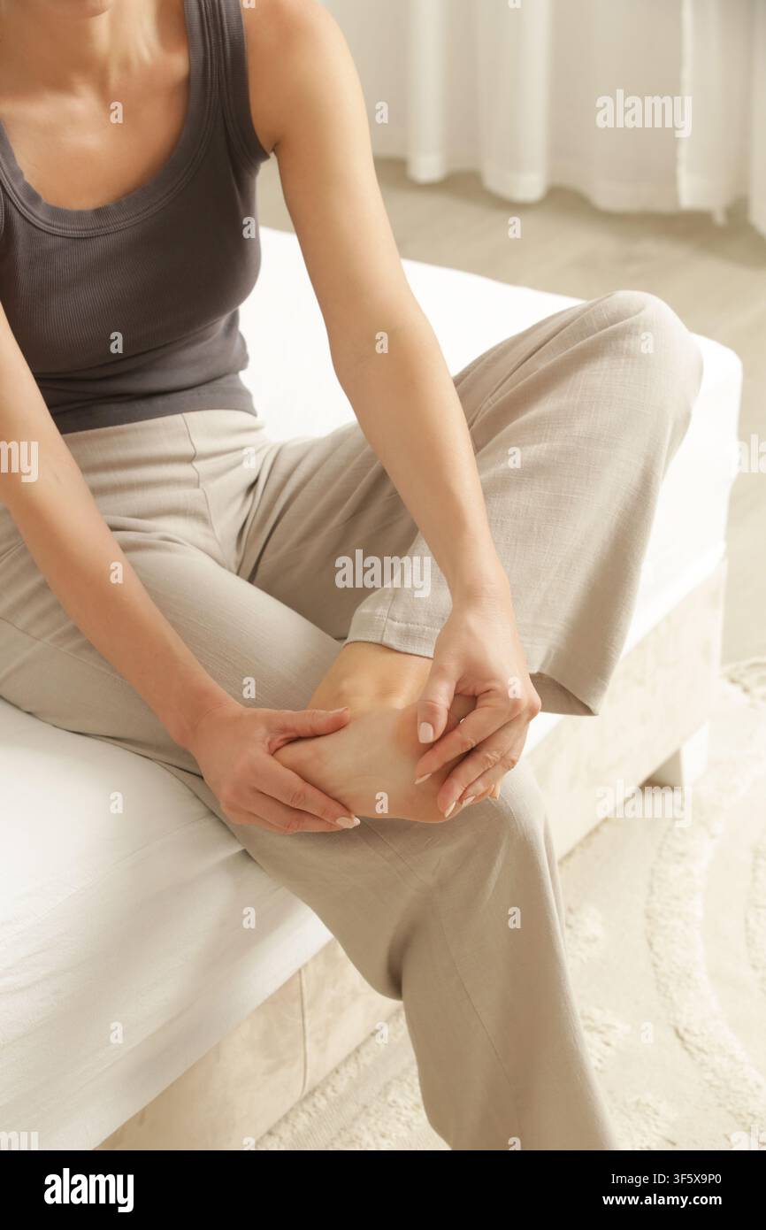 Donna che allunga il piede mentre prova un crampo muscolare, concetto di sollievo dal dolore Foto Stock