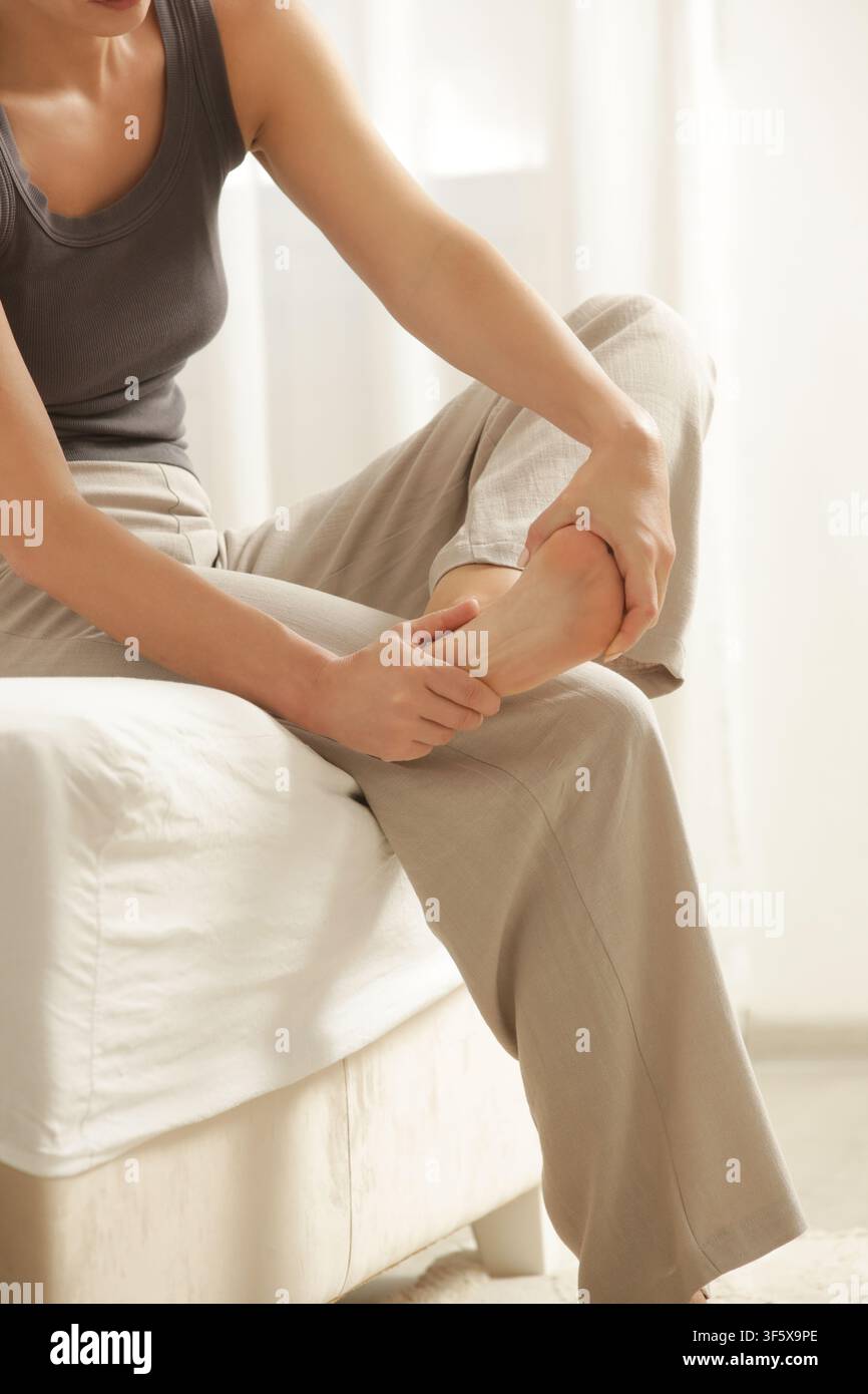 Donna che allunga il piede mentre prova un crampo muscolare, concetto di sollievo dal dolore Foto Stock