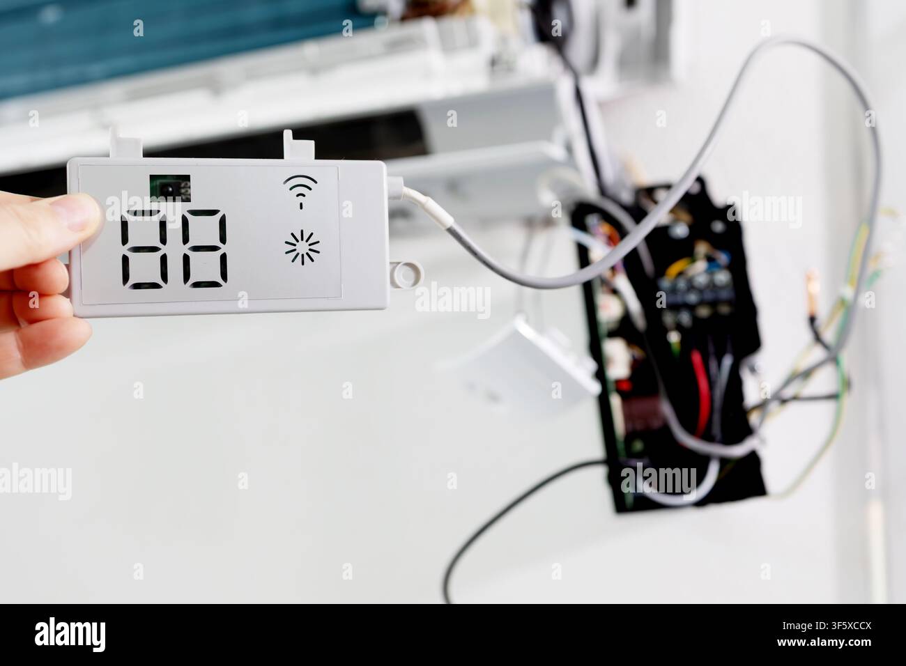 Tecnico che tiene un modulo display per condizionatore a sistema split. Concetto di riparazione e manutenzione Foto Stock