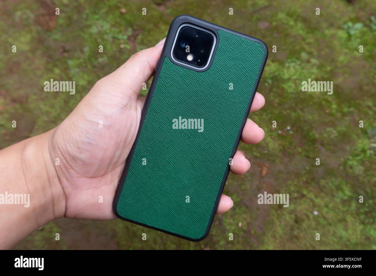 Vista posteriore di uno smartphone verde tenuto in mano Foto Stock
