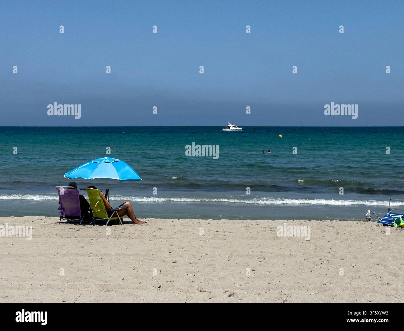 Coppia che si rilassa su sedie a Playa del Pudrimel, La Manga, Murcia, Spagna - Immagine stock catturata con smartphone