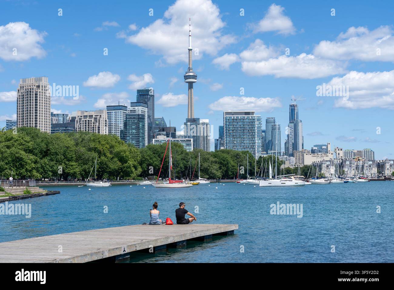 Due persone sedute su un terrazzo di legno nel Trillium Park e osservano lo skyline di Toronto, Canada Foto Stock