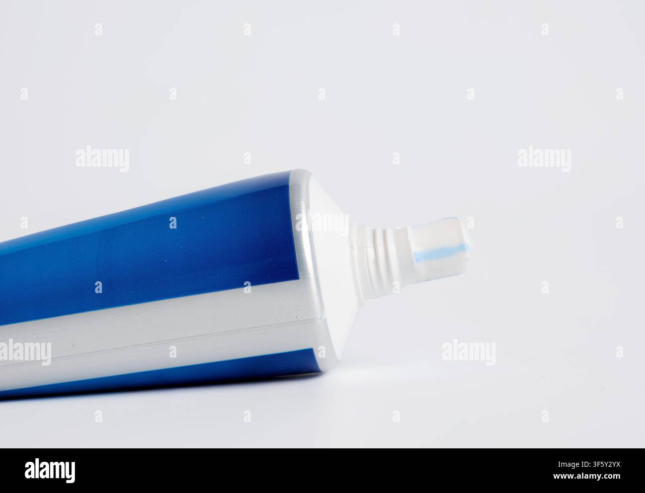 Tubo di dentifricio appoggiato su uno sfondo bianco immacolato, che simboleggia l'igiene orale essenziale e le routine quotidiane di cura dentale per un sorriso sano Foto Stock