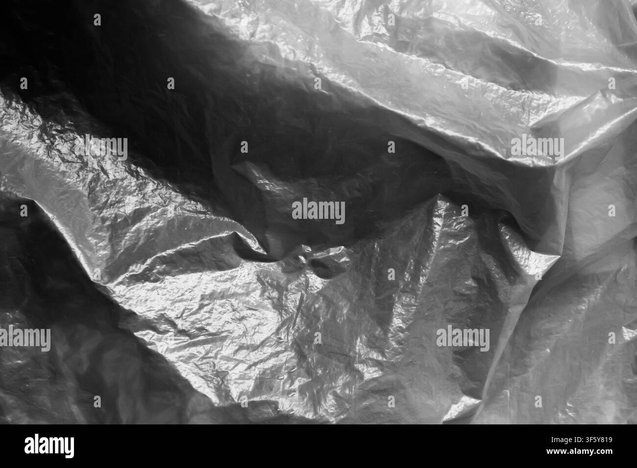 Una texture di plastica sgualcita, superficie rugosa, film lucido, astratto monocromatico, materiale riflettente, primo piano Foto Stock